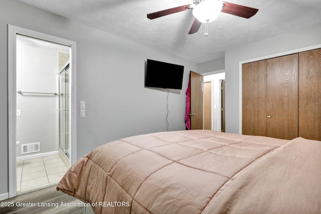 910 Pecos Dr, Lansing, MI 48917 - bedroom featuring a closet, baseboards, wood finished floors, a ceiling fan, and a textured ceiling