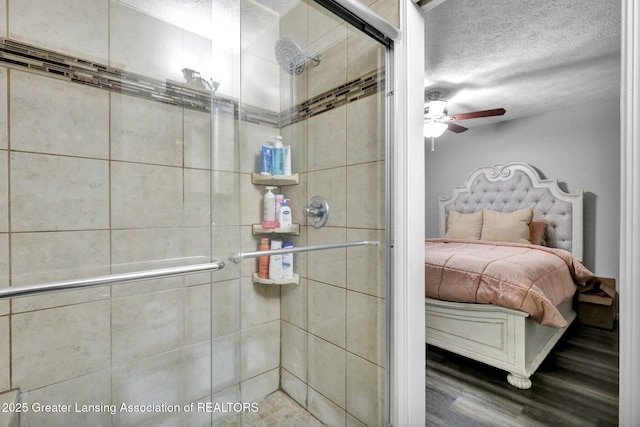 910 Pecos Dr, Lansing, MI 48917 - bathroom featuring a ceiling fan, a shower stall, wood finished floors, and a textured ceiling