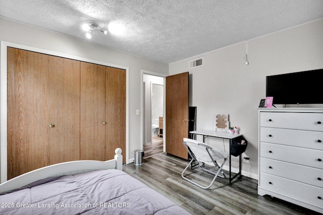910 Pecos Dr, Lansing, MI 48917 - bedroom featuring wood finished floors, a textured ceiling, a closet, and baseboards