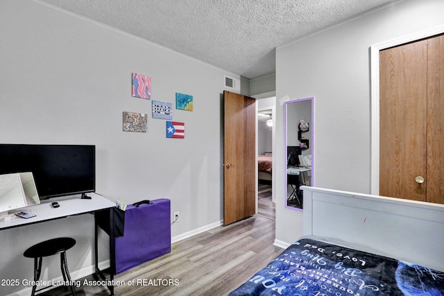 910 Pecos Dr, Lansing, MI 48917 - bedroom featuring wood finished floors, a textured ceiling, baseboards, and an office area