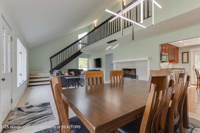 dining space with stairway, a tiled fireplace, a towering ceiling, and baseboards
