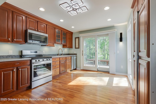 kitchen with stainless steel appliances, light wood-style floors, recessed lighting, glass insert cabinets, and baseboards