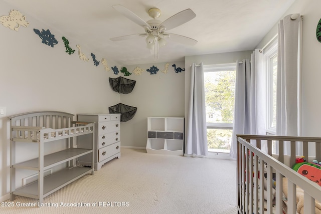 bedroom featuring carpet floors, baseboards, a nursery area, and ceiling fan