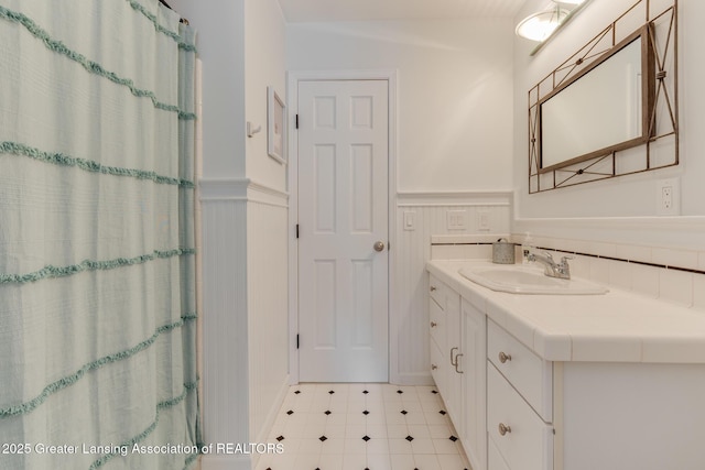 bathroom with a wainscoted wall, vanity, and a shower with shower curtain
