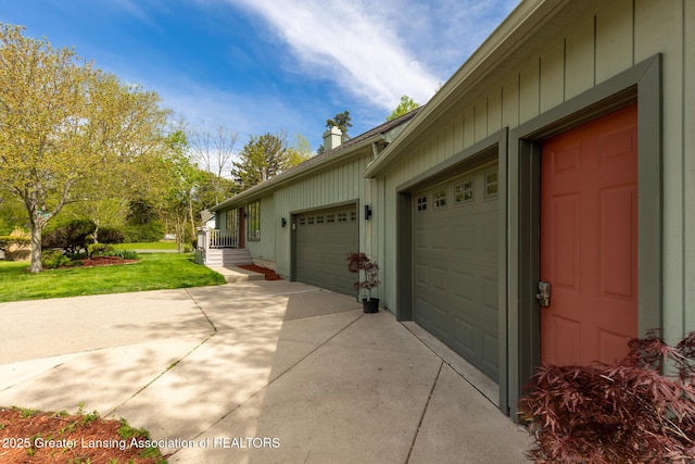 view of side of home featuring concrete driveway, a lawn, a garage, and board and batten siding