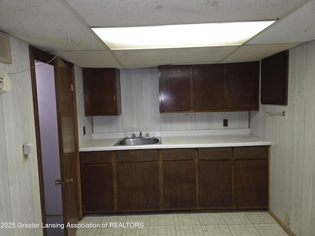 526 Fenton St, Lansing, MI 48910 - kitchen featuring a sink, a drop ceiling, light countertops, wooden walls, and dark brown cabinets
