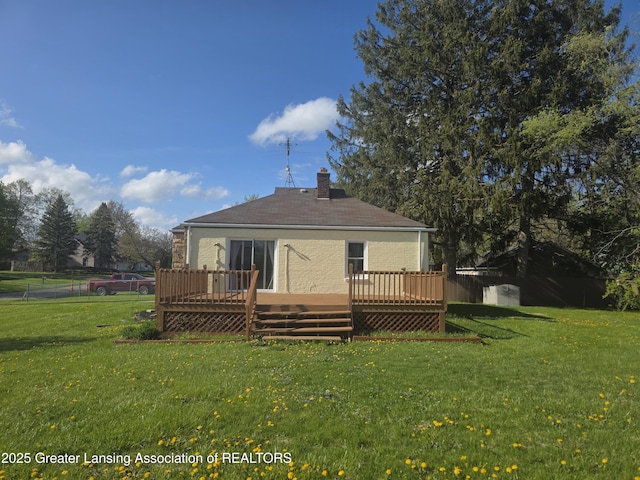 rear view of house with a wooden deck, a yard, and a chimney