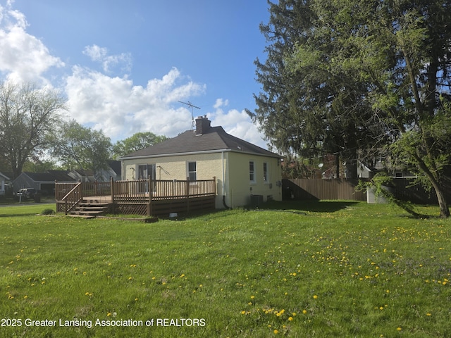 back of property featuring a deck, a chimney, and central AC