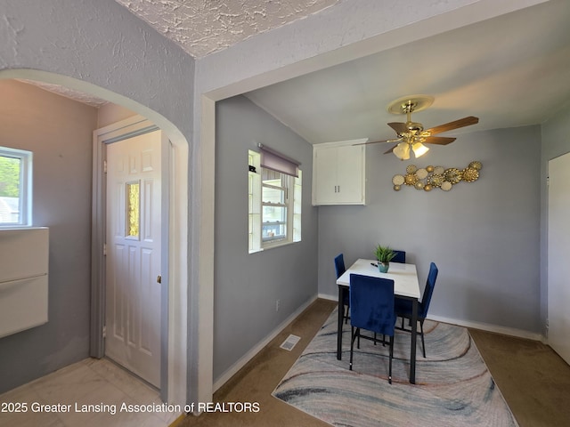 dining space featuring healthy amount of natural light, arched walkways, and a ceiling fan