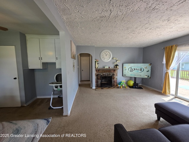 carpeted living area with arched walkways, baseboards, a stone fireplace, and a textured ceiling