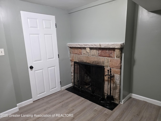detailed view of wood finished floors, a fireplace, and baseboards