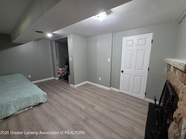 bedroom featuring light wood-style floors, a fireplace, and baseboards