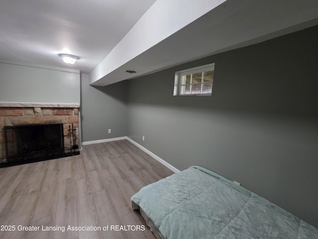 bedroom featuring wood finished floors, a fireplace, and baseboards