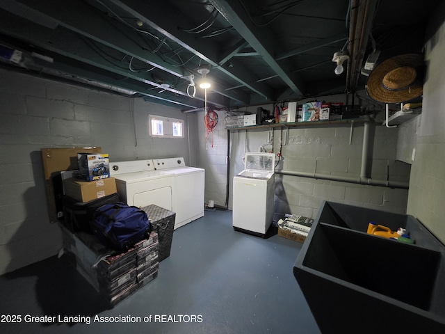 below grade area featuring washing machine and clothes dryer and concrete block wall