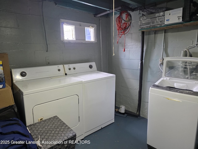 clothes washing area featuring separate washer and dryer and concrete block wall