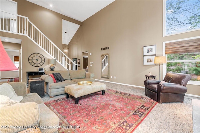 carpeted living room with a towering ceiling, stairway, baseboards, and recessed lighting