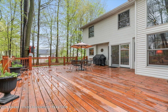 wooden terrace with outdoor dining space and a grill