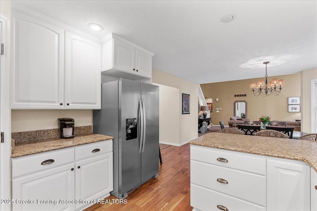 kitchen with stainless steel fridge with ice dispenser, white cabinetry, a chandelier, light wood-type flooring, and pendant lighting