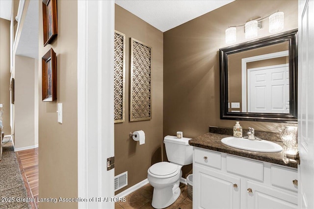 bathroom featuring toilet, baseboards, and vanity