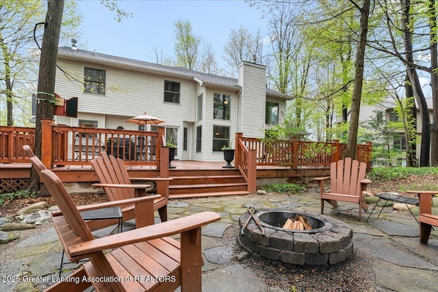 back of house with a fire pit, a chimney, a patio area, and a deck