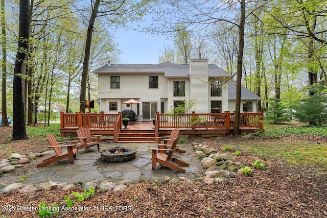 back of house with a fire pit, a wooden deck, a chimney, and a patio
