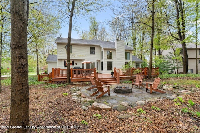rear view of house featuring an outdoor fire pit, a deck, and a chimney