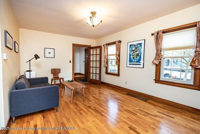 sitting room with light wood finished floors, healthy amount of natural light, baseboards, and french doors