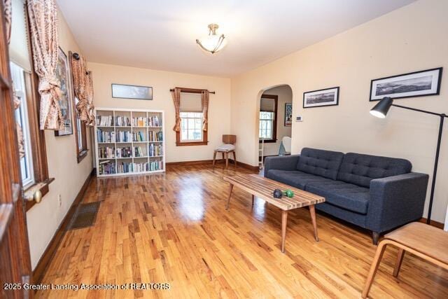 living area featuring arched walkways, wood finished floors, and baseboards