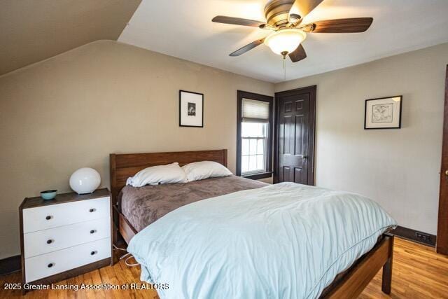 bedroom featuring wood finished floors, lofted ceiling, and a ceiling fan
