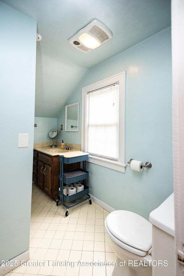 bathroom with vaulted ceiling, toilet, vanity, and baseboards