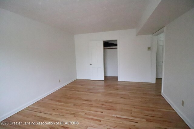 unfurnished bedroom with light wood-style flooring, a closet, and baseboards
