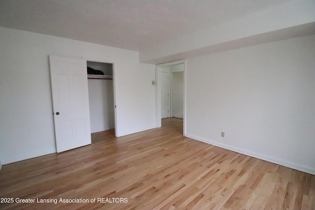 unfurnished bedroom with light wood-style floors and a closet