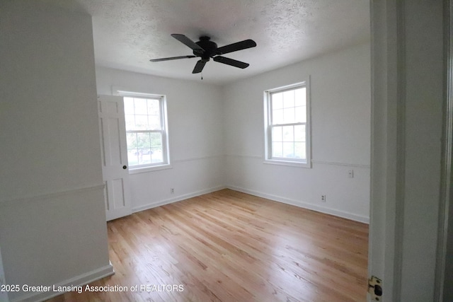 spare room with plenty of natural light, wood finished floors, a textured ceiling, and baseboards