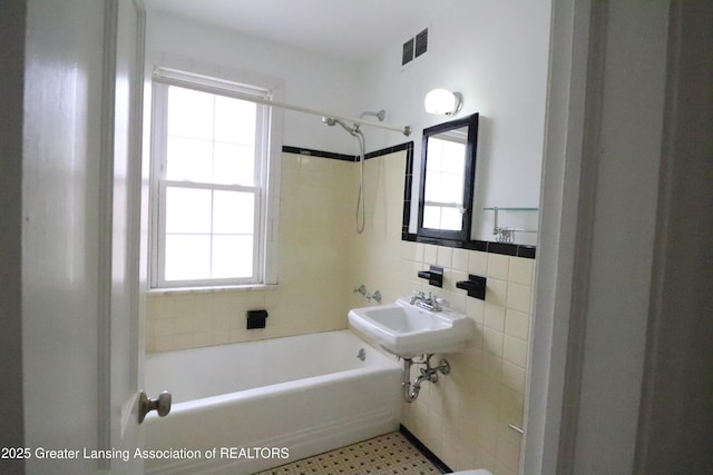 full bathroom with tile walls, shower / tub combination, and wainscoting