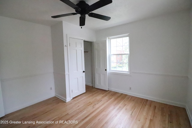 unfurnished bedroom with wood finished floors, a closet, baseboards, and a ceiling fan