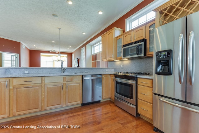 kitchen with stainless steel appliances, ornamental molding, glass insert cabinets, backsplash, and light wood-style floors