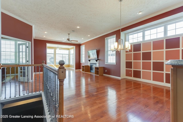 foyer with a textured ceiling, ornamental molding, wood finished floors, baseboards, and a chandelier