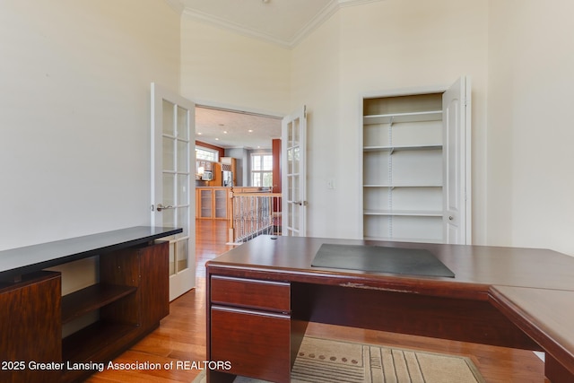 unfurnished office featuring crown molding, french doors, and light wood-style flooring