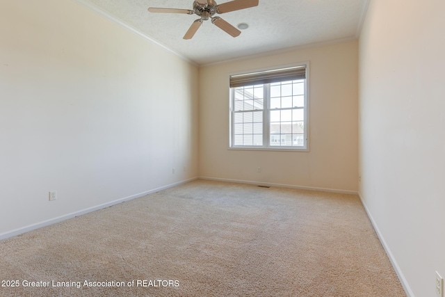 carpeted empty room featuring crown molding, a ceiling fan, and baseboards