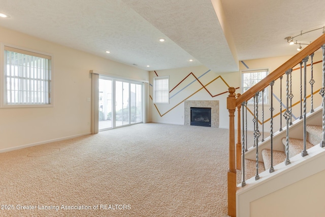 unfurnished living room featuring a textured ceiling, carpet flooring, a tile fireplace, recessed lighting, and baseboards