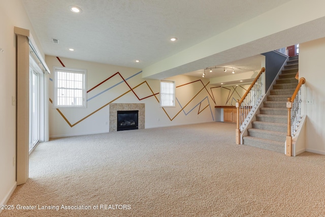 unfurnished living room featuring carpet, baseboards, stairway, recessed lighting, and a tiled fireplace