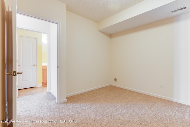 spare room featuring light carpet and baseboards