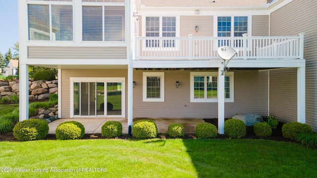 back of property with a lawn, a wooden deck, and a patio