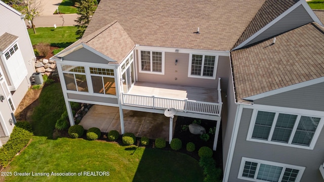 back of house featuring central AC, a sunroom, a shingled roof, and a yard