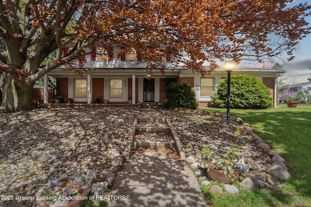 obstructed view of property featuring brick siding, a porch, and a front yard