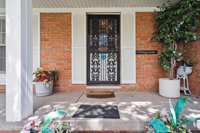 doorway to property with brick siding and covered porch