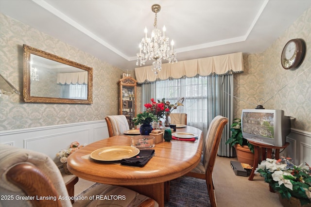 carpeted dining room with a chandelier, wallpapered walls, wainscoting, and a tray ceiling