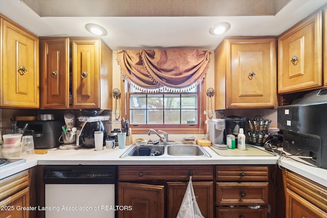 kitchen featuring white dishwasher, a sink, light countertops, and recessed lighting