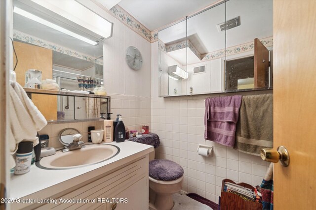bathroom with tile walls, toilet, and vanity