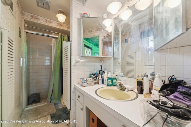 full bathroom with tile walls, a shower stall, vanity, and backsplash